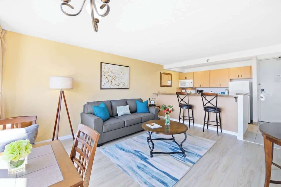 This open-concept living area seamlessly connects the comfortable seating space with the adjacent dining table and a convenient breakfast bar leading into the kitchen.