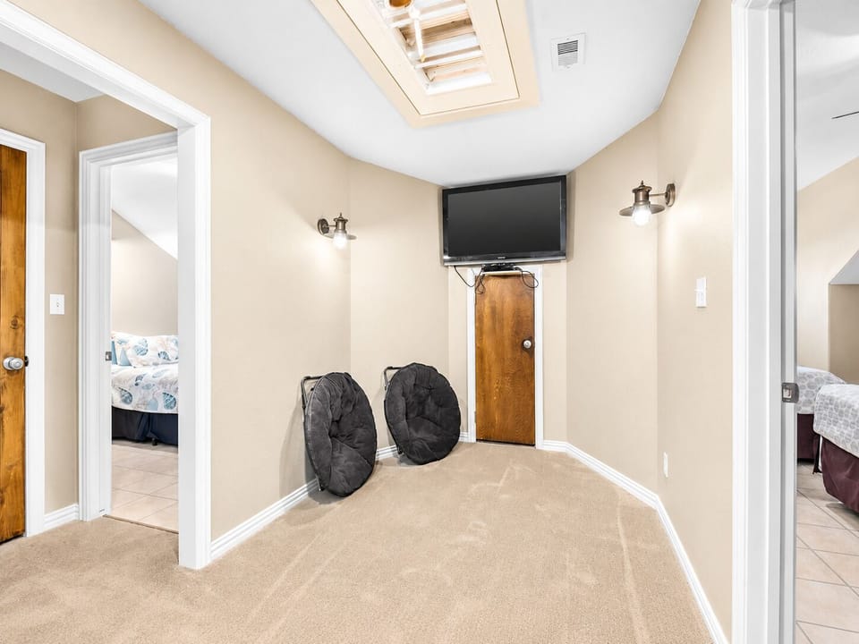 Dedicated laundry area with two front-loading machines, storage space, a mounted TV, and easy access from the adjoining hallway.