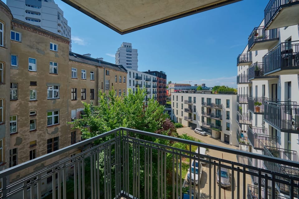 Balcony view showcasing nearby architecture and greenery, blending urban living with nature.

