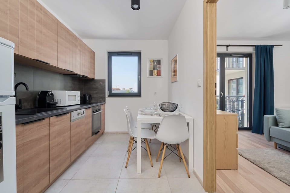 Fully equipped kitchen with wooden cabinets, sleek black countertops, and a small dining area.

