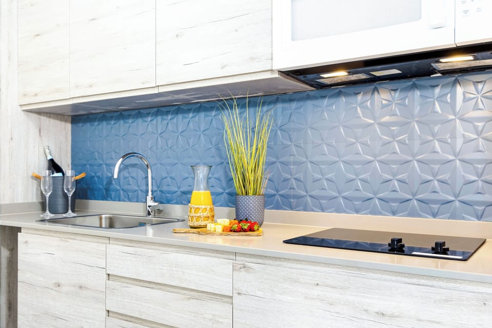 Your modern kitchen features sleek countertops, a stylish blue geometric backsplash, and everything you need to prepare your favorite meals in comfort.