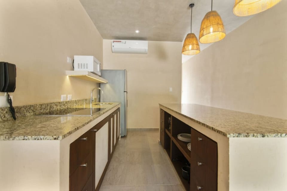 Open kitchen with granite counters, fridge, and warm pendant lighting.