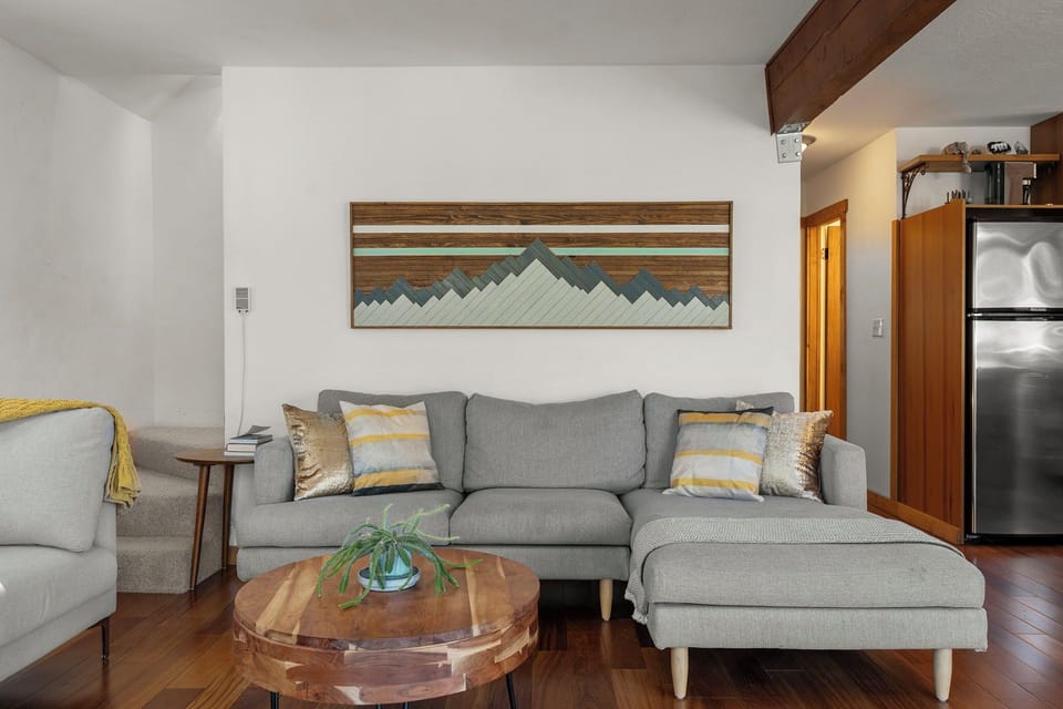 Relax on plush gray sofas while mountain art and warm wood beams create your perfect cozy retreat.