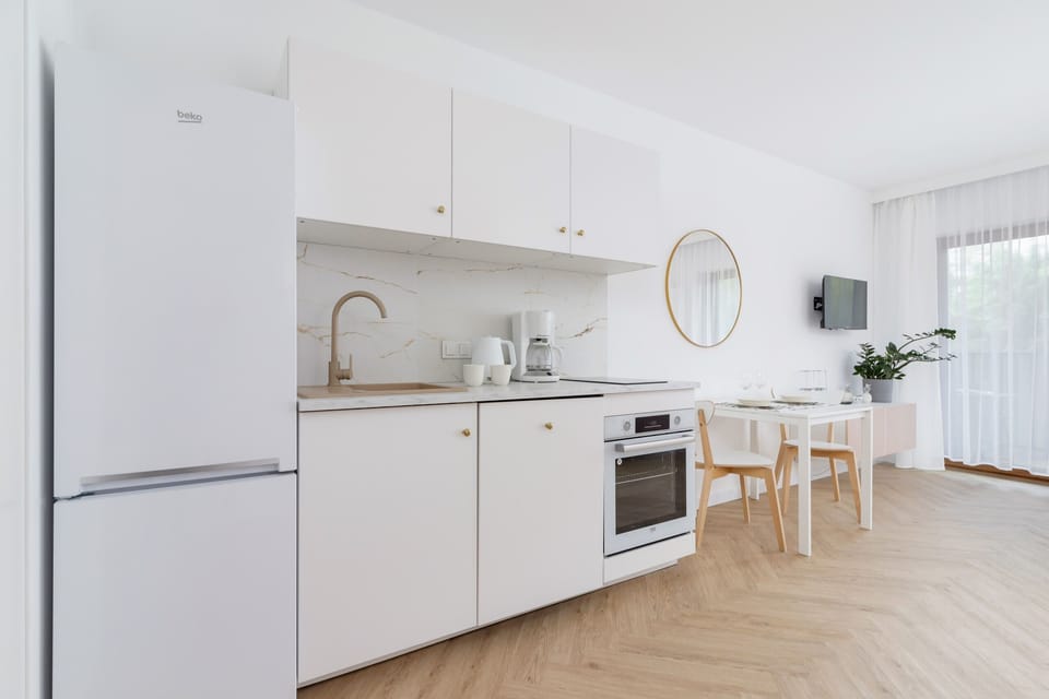 Fully equipped kitchen with white cabinetry, a fridge, and modern appliances.

