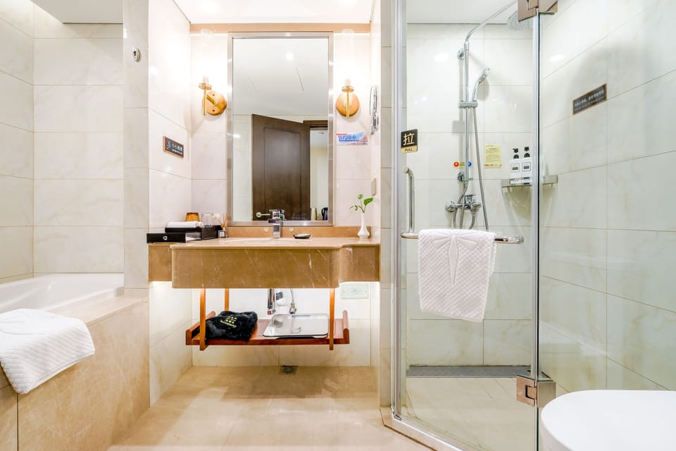 Standard Suite | Bathroom | Rainfall showerhead, hair dryer, slippers, towels