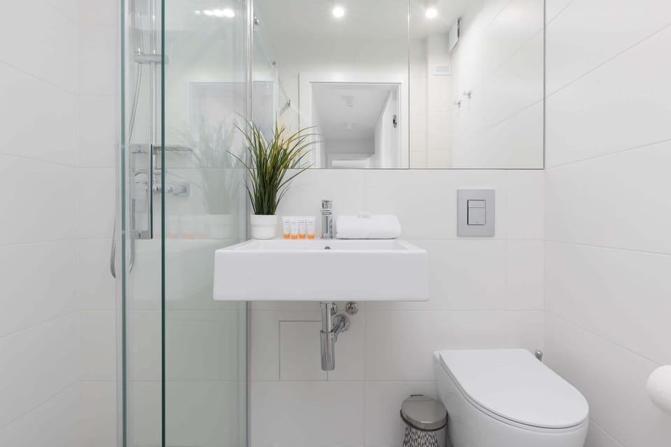 Modern bathroom with a sleek white design, a compact sink, and minimalist decor.


