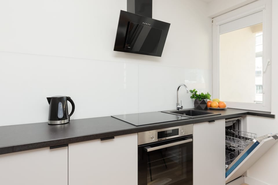 Fully equipped kitchen with sleek black countertops, a kettle, and modern appliances.

