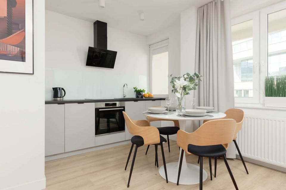 Dining area and kitchen with a minimalist table and modern chairs, offering a sleek design.

