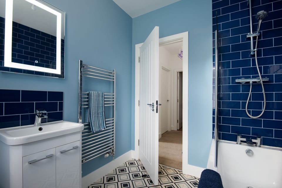 Walltown Farm Cottage - first floor family bathroom with shower over bath, WC, and basin with illuminated mirror above