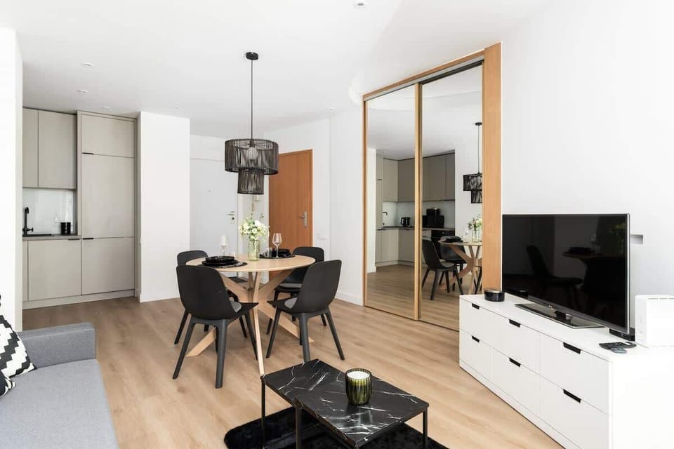 Spacious living and dining area with a modern table, stylish furniture, and natural light.

