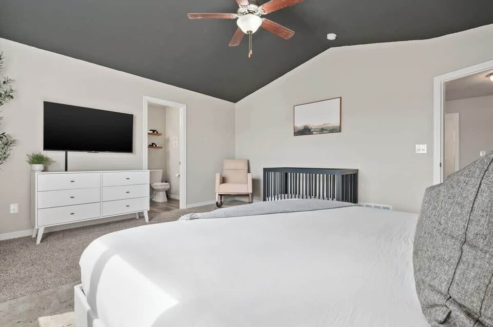 Master bedroom with king bed, crib bed, 50" TV and attached bathroom