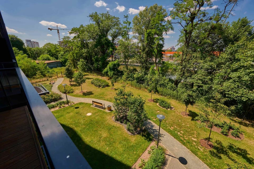 Scenic garden view from the balcony, featuring a landscaped pathway and tall trees.

