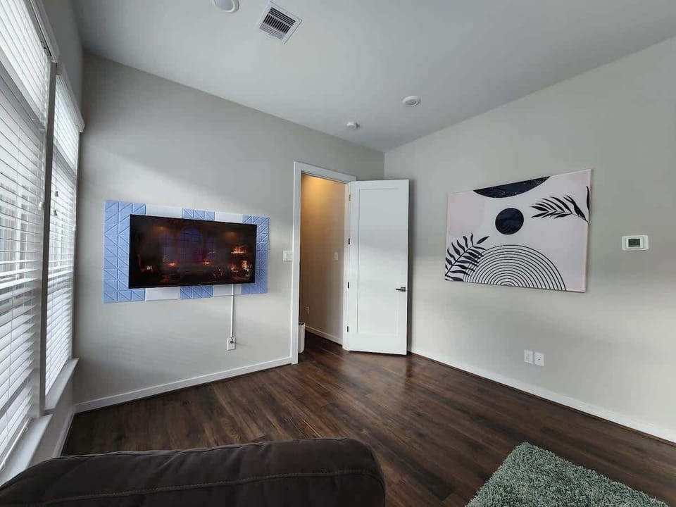 50-inch TV takes center stage, providing entertainment and relaxation. Sleek design of the TV blends seamlessly with the overall aesthetic, and its positioning allows for comfortable viewing from the bed and  backdrop complements the mid-century vibe