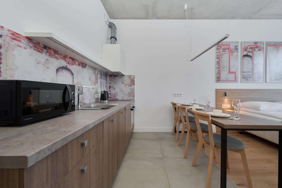 Fully equipped kitchen with sleek wooden cabinets and a cozy dining area in the background.

