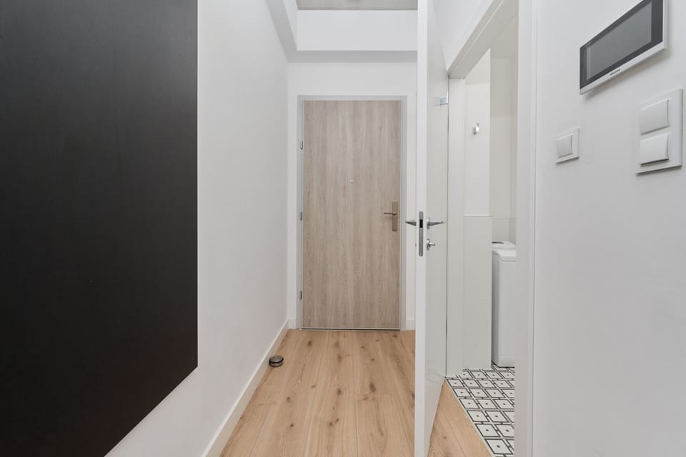 Hallway in the apartment with sleek finishes, natural wood doors, and a contemporary aesthetic.

