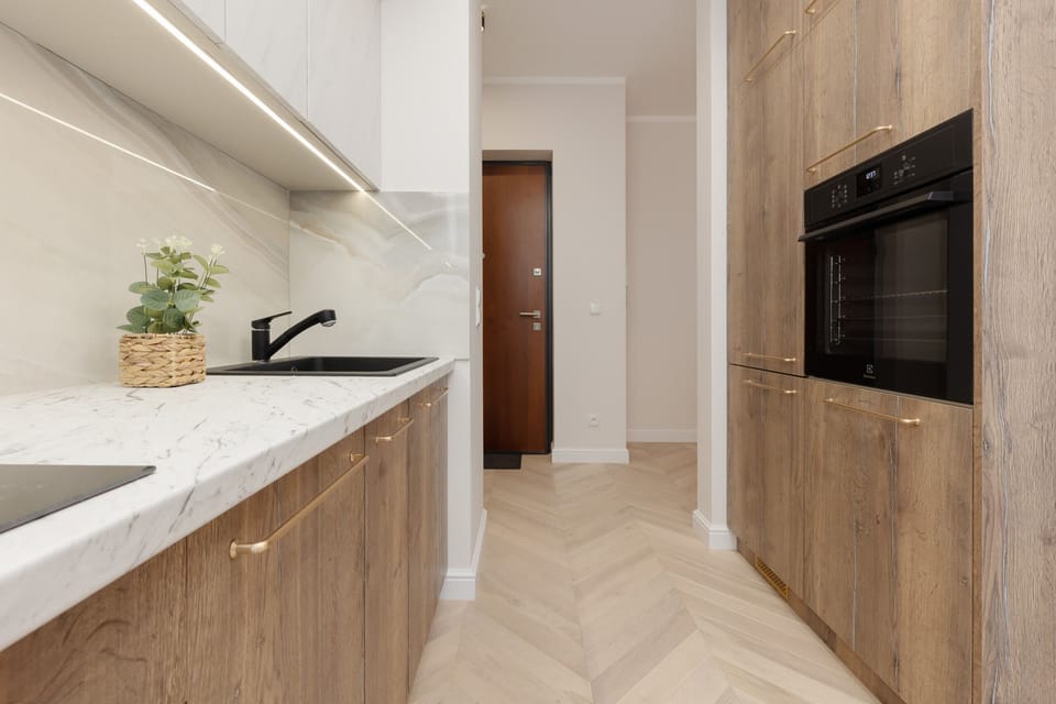 Fully equipped kitchen with sleek countertops, wooden cabinets, and a built-in oven.

