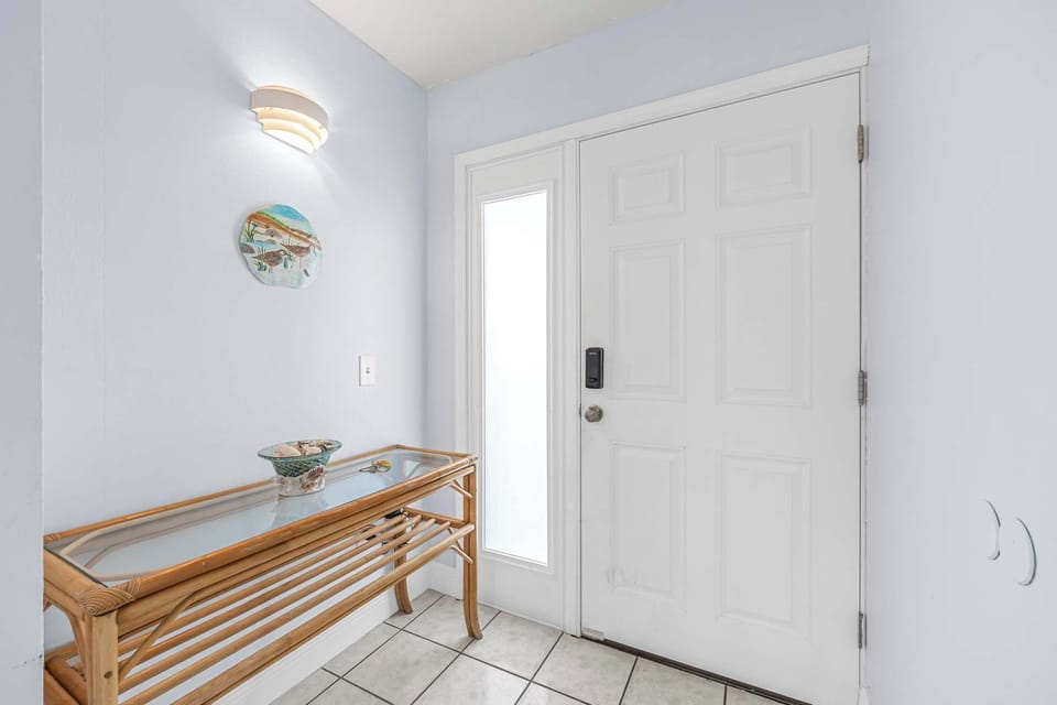 Entryway with a glass-top bamboo console table and natural light from a side window