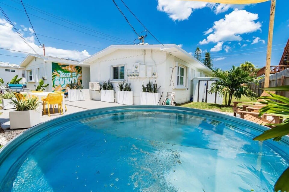 Relax by the round pool in this bright outdoor patio with tropical plants and colorful seating.