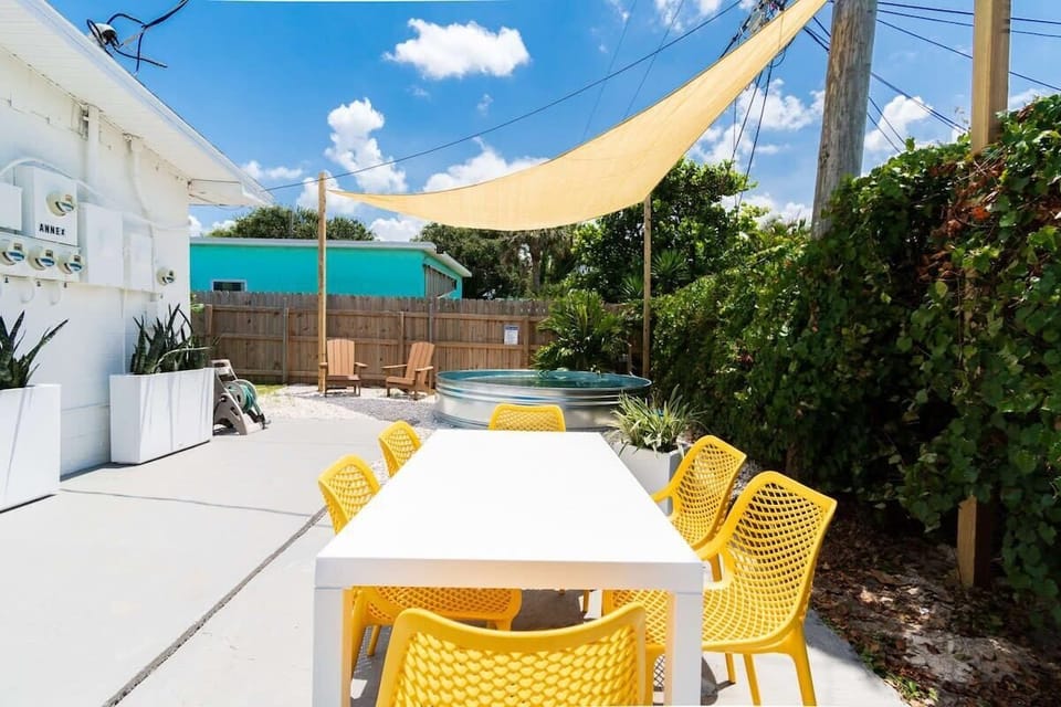 Outdoor dining area with yellow chairs and shaded seating near a small pool