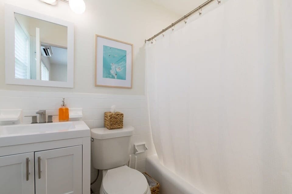 Clean bathroom with white fixtures and a framed wall print