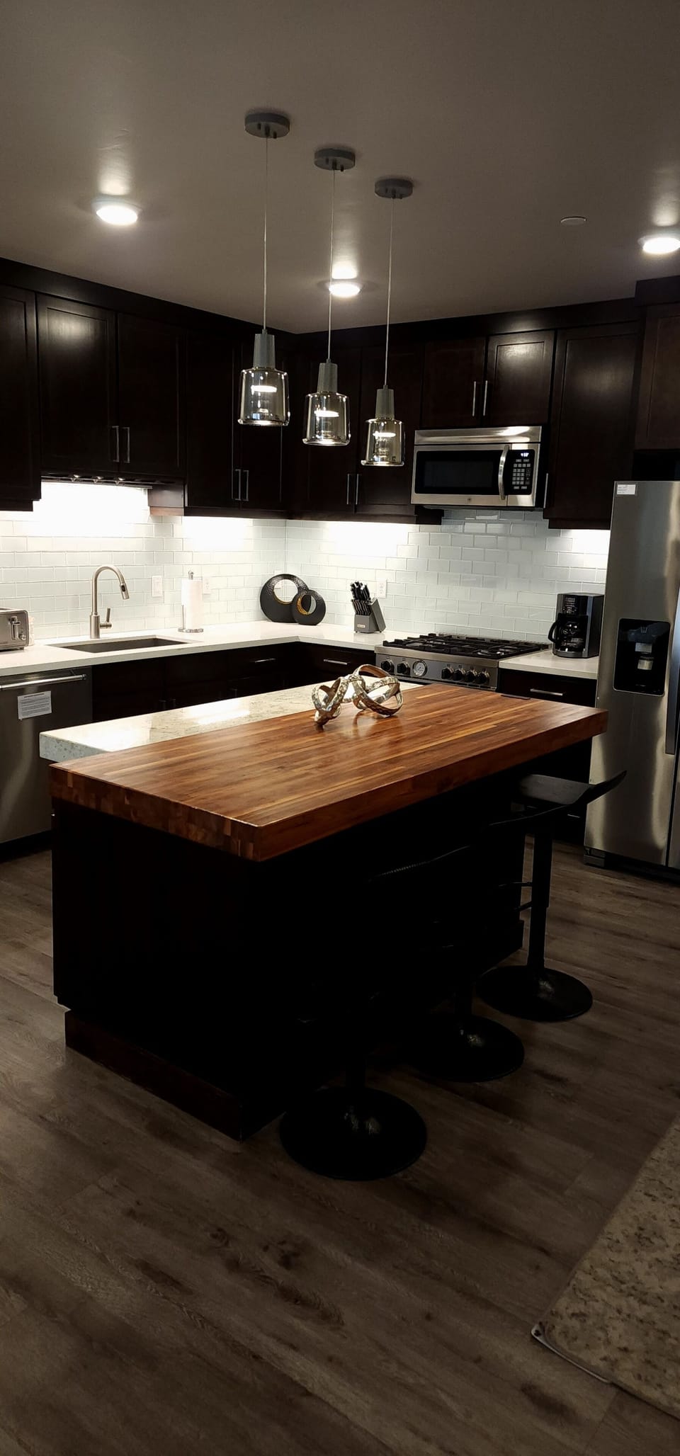A sleek, modern kitchen featuring dark wood cabinetry, stainless steel appliances, and a butcher block island perfect for meal prep or casual dining.