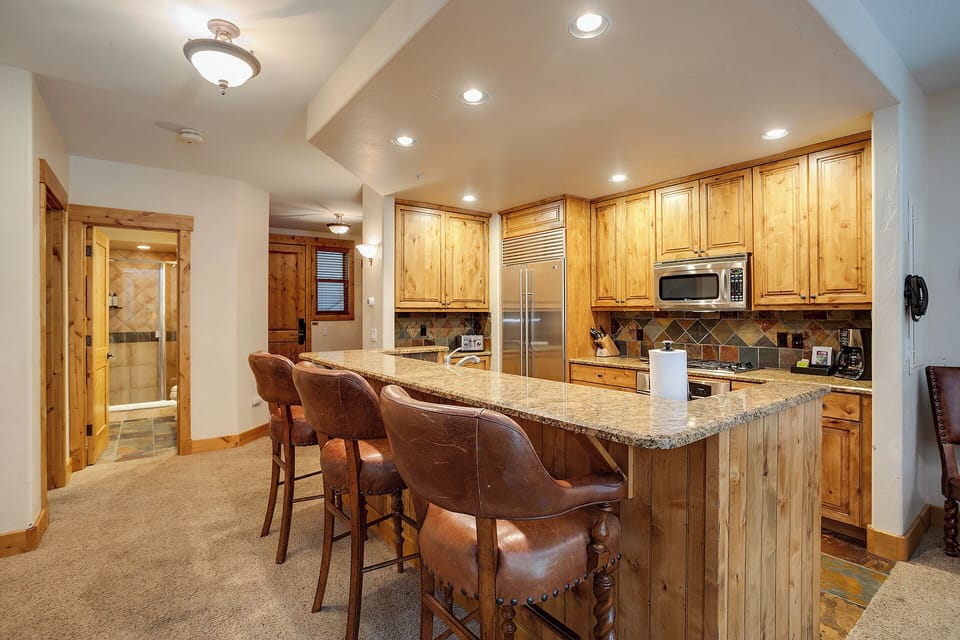 Your fully-equipped kitchen features granite countertops and rustic wood cabinetry, perfect for preparing meals with mountain lodge charm.