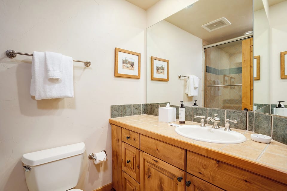 Refresh in your private bathroom with warm wood accents, a spacious tiled shower, and plush towels ready for your arrival.