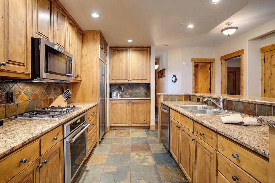 Your gourmet kitchen features warm wood cabinetry, granite countertops, and stainless steel appliances perfect for preparing memorable meals together.