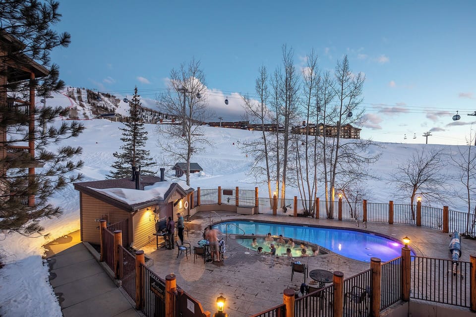 Mountain resort features heated pool with ski slopes backdrop and gondola access.
