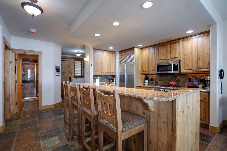 Your fully-equipped rustic kitchen features granite countertops, stainless steel appliances, and a spacious island with bar seating for memorable meals together.