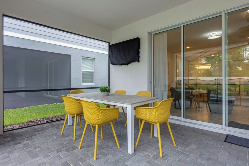 Dining area under the covered patio roof with a TV, loungers, and dining area.
