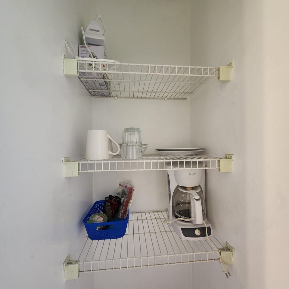 coffee pot, few snacks, cutlery, and dishes in small closet 