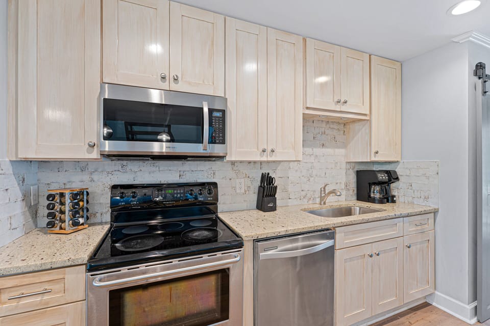 Stainless steel appliances—including a smooth-top range, built-in microwave, dishwasher, and refrigerator—create a cohesive, modern look.