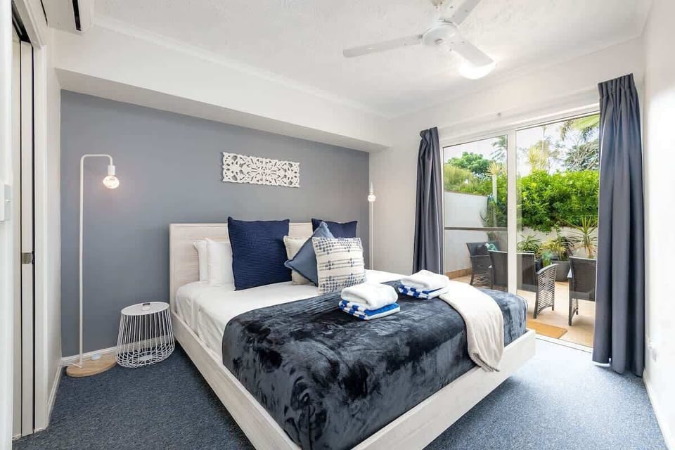 Rest in the primary bedroom, where a king bed, split-system air conditioning and heating, a ceiling fan, and direct outdoor access create a calm retreat with an easy indoor-outdoor feel.