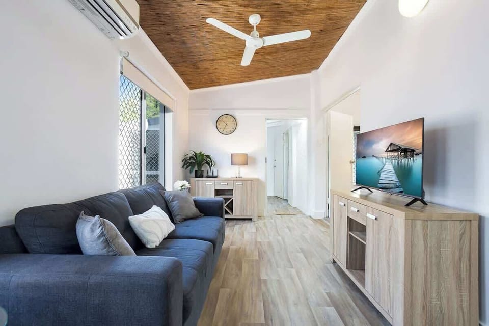 Relax in the light-filled living area, where a three-seater sofa, air conditioning, and a TV create a welcoming space to unwind after a day by the beach.
