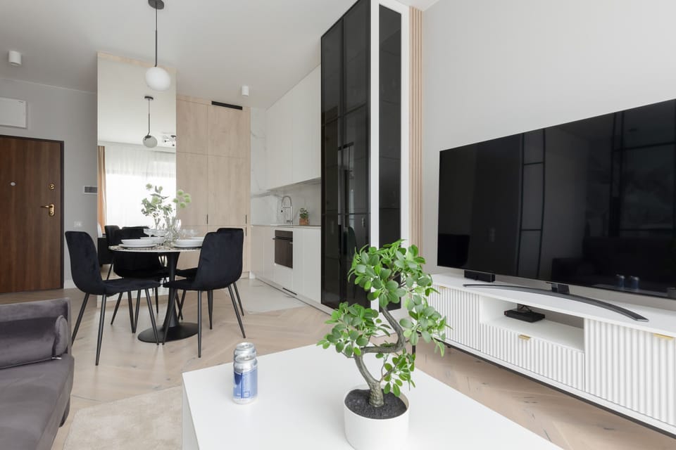 Open-plan living and dining area featuring a sleek design and a wall-mounted TV.

