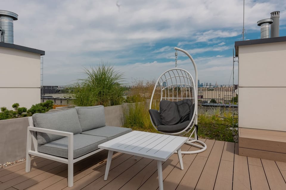 Rooftop seating area with a hanging chair and greenery, perfect for unwinding.

