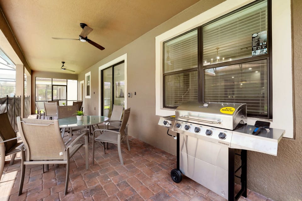 Covered private patio with dining seating, ceiling fans, and a full-size stainless-steel grill for relaxed outdoor meals.
