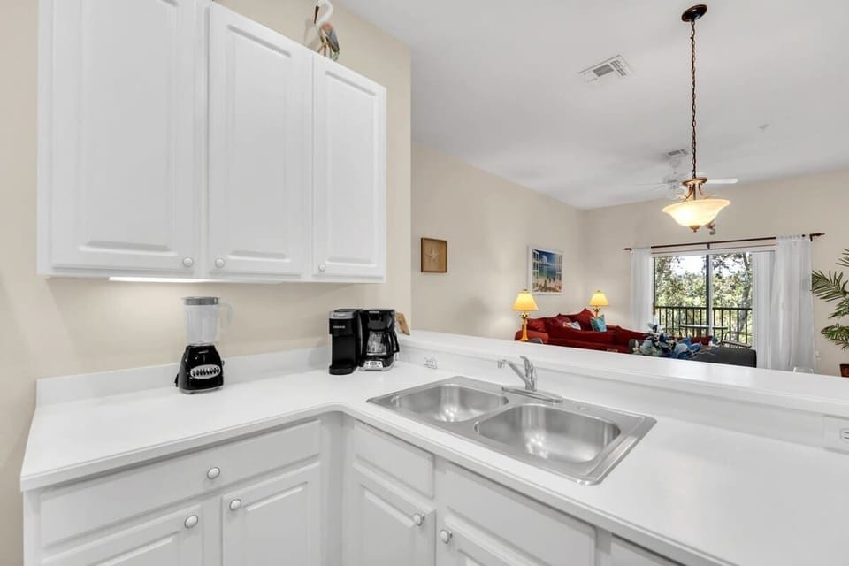 Modern kitchen with white cabinetry and a view into the cozy living area.