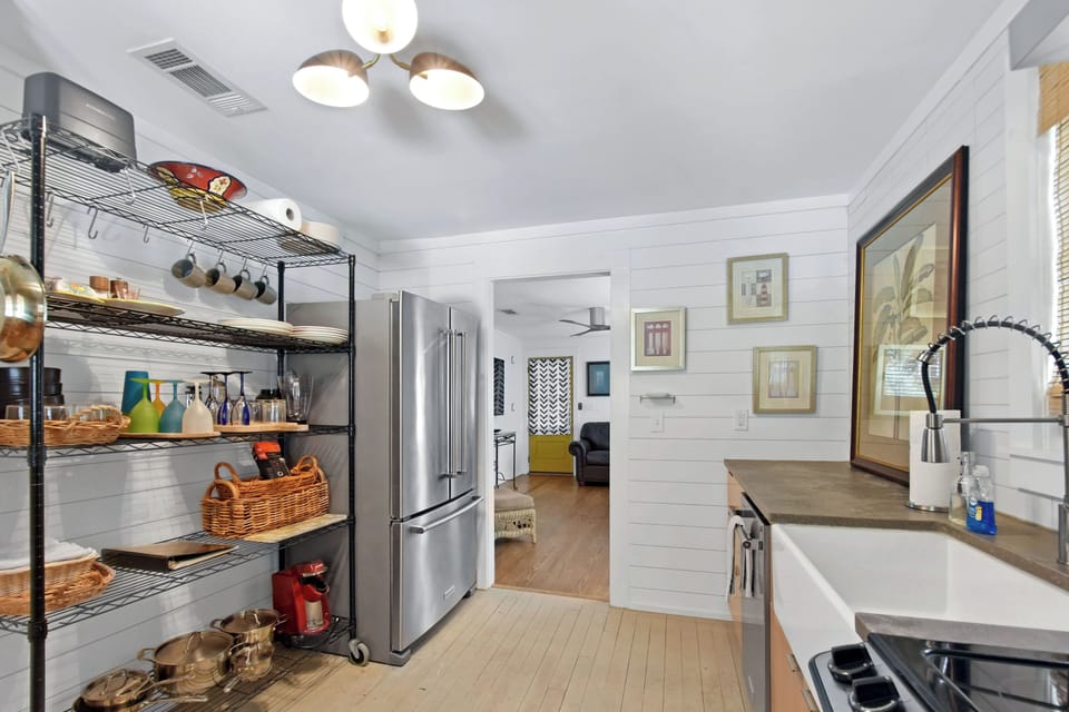 Kitchen Pantry Wall and Full-Size Fridge - Kitchen view with full-size refrigerator, open shelving, farmhouse sink, and stocked pantry wall.