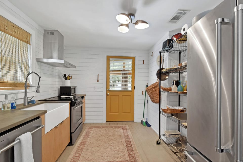 Kitchen Entry and Open Shelving - Rear entry opens into the kitchen with stainless appliances, open shelving, and counter space.