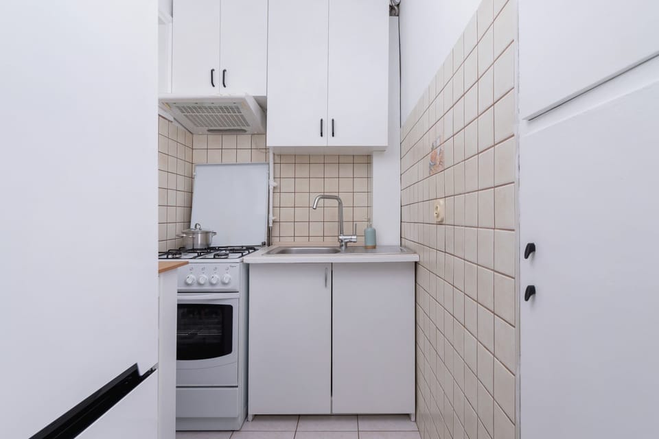 Compact kitchen with white cabinets, tiled backsplash, and essential appliances for cooking.

