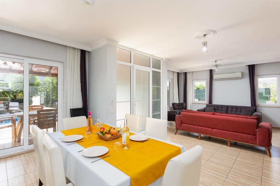 Open-plan living room with sofas, dining area, kitchen, A/C, WiFi internet, and satellite TV