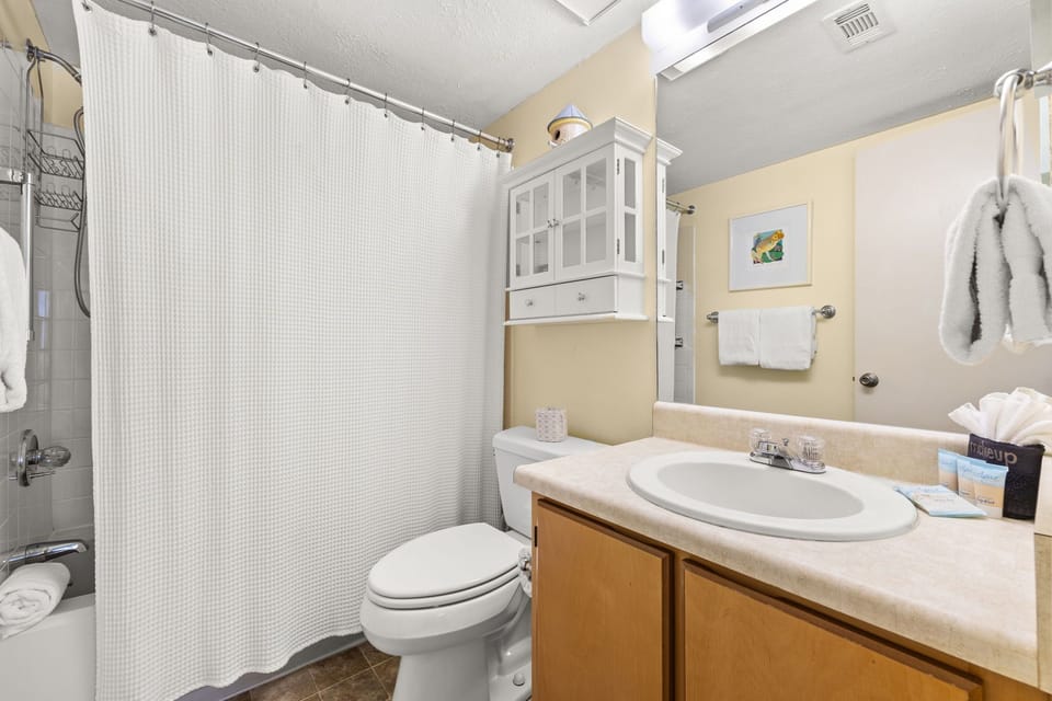 Clean bathroom with a shower and storage cabinet