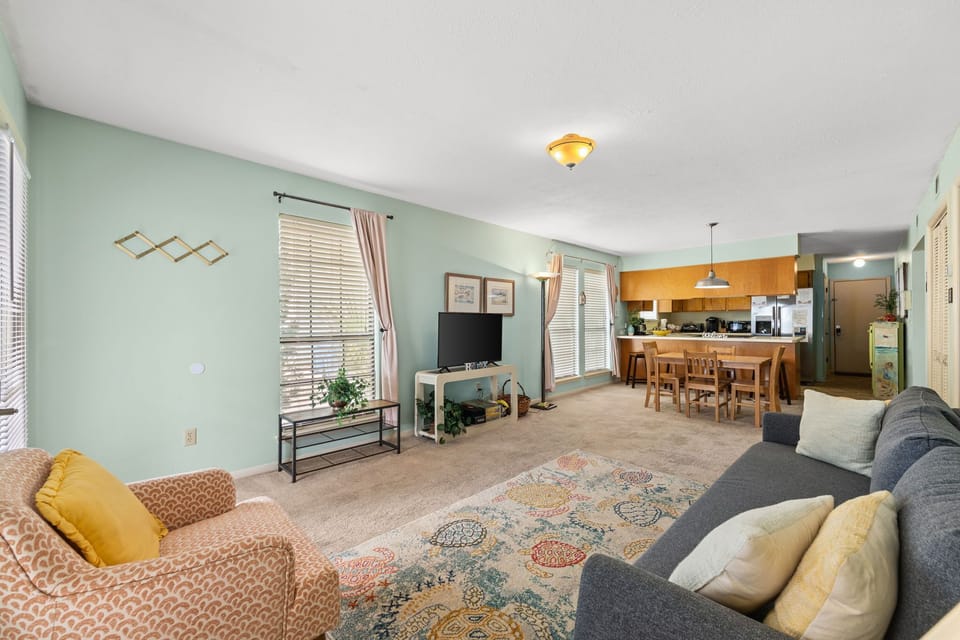 Open living area with soft green walls and natural light connecting to the kitchen and dining space