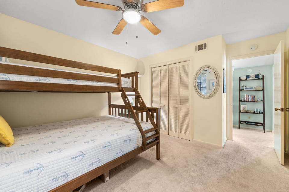 Cozy bedroom featuring a wooden bunk bed and soft carpeting.