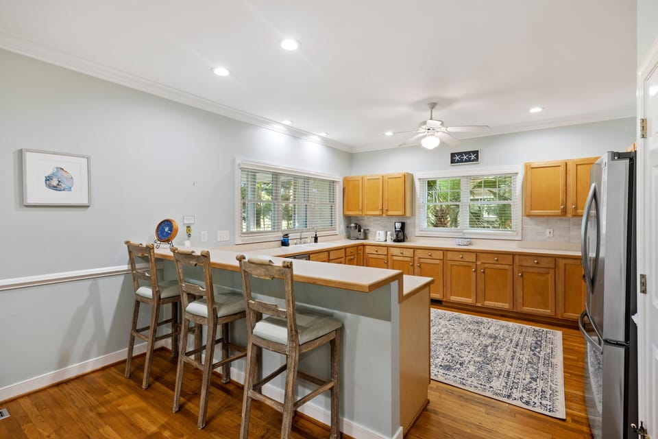 Kitchen area with lots of counter space, upgraded appliances, and three bar stools at the breakfast bar.