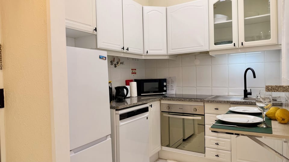 Cozinha completa totalmente equipada e com pequena mesa de apoio para dois