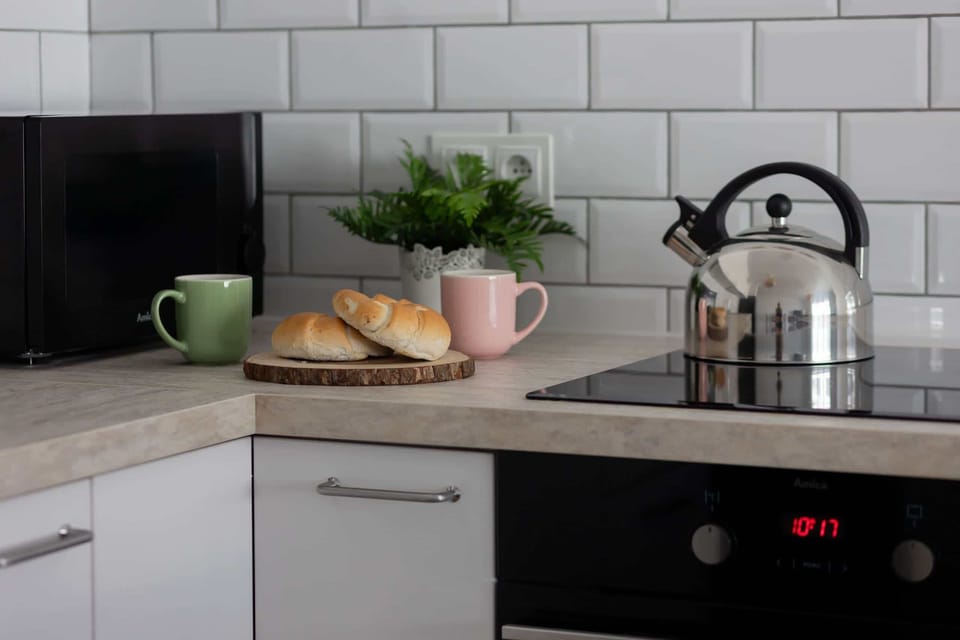 A close-up of a kitchen counter with a kettle, a plant, and a loaf of bread adding a homey vibe.

