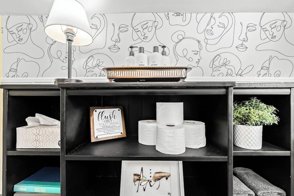 Bathroom cubby includes extra toilet paper, tissue paper, and a nightlamp